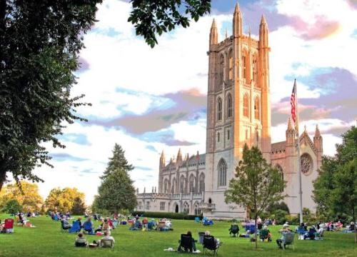 The Trinity College Chapel with students sitting on the grass